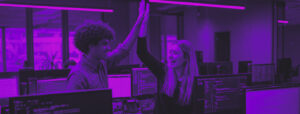 Two developers high-fiving in a modern office environment